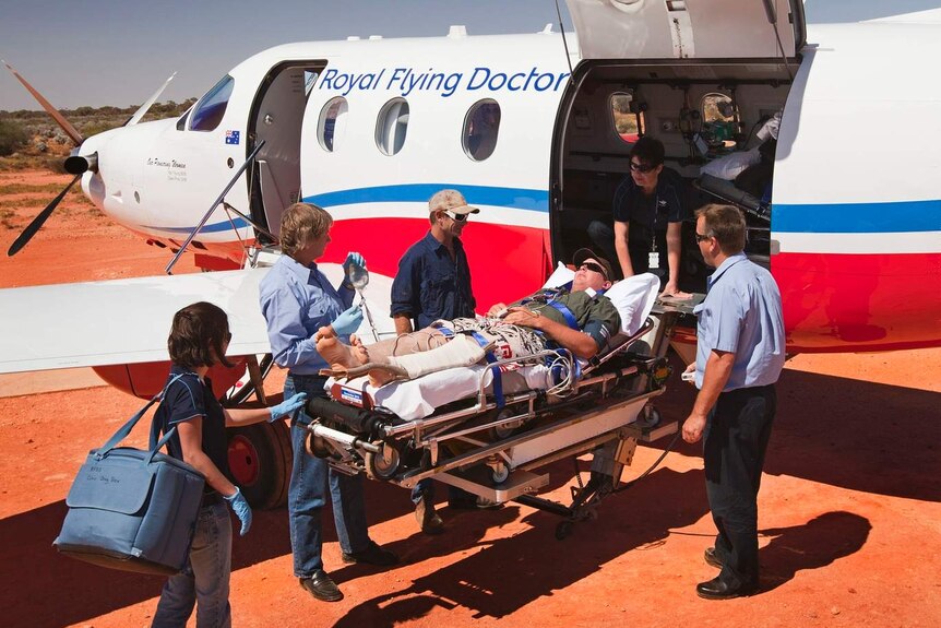 Man on stretcher in desert being loaded onto small aircraft