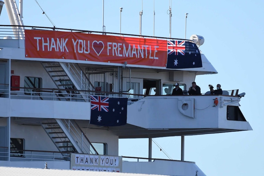 A red banner reading 'THANK YOU FREMANTLE' and two Australian flags hang from the top of the Artania cruise ship.