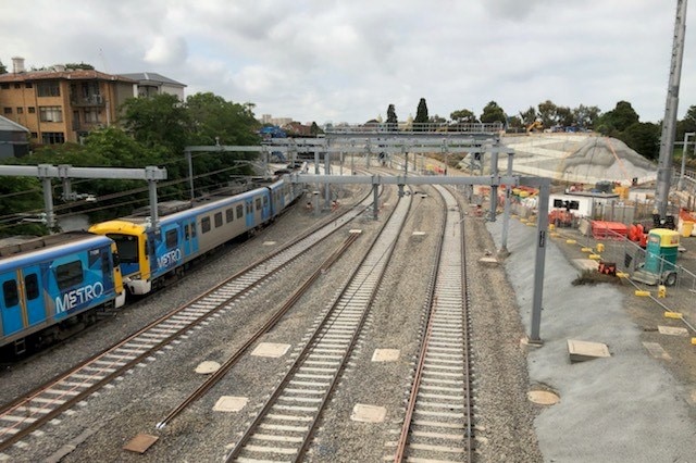 A train is seen on train tracks, while construction equipment is seen nearby.