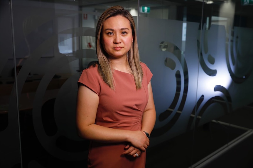 Mary Wu debout dans le hall de son bureau de Canberra.