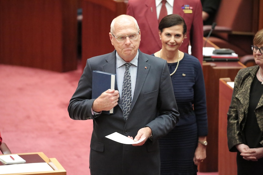 Jim Molan holds a bible while being sworn into the Senate 