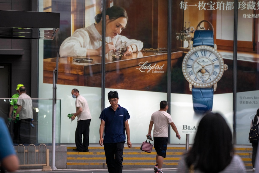 在北京的一家高档购物中心，人们从瑞士奢侈手表零售商宝珀的广告牌前走过。