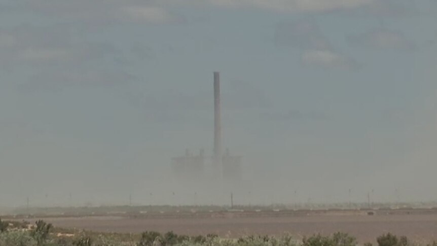 A think brown cloud shrouds the landscape.  A power station stack is the only thing visible.