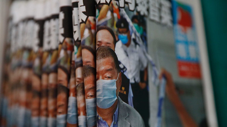 A pile of newspapers with a man on the cover and a headline in Chinese script.