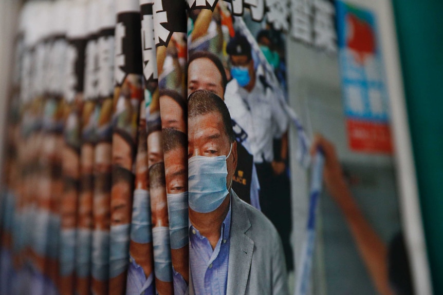 A pile of newspapers with a man on the cover and a headline in Chinese script.