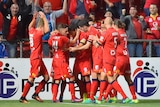 Adelaide United players hug after scoring a goal
