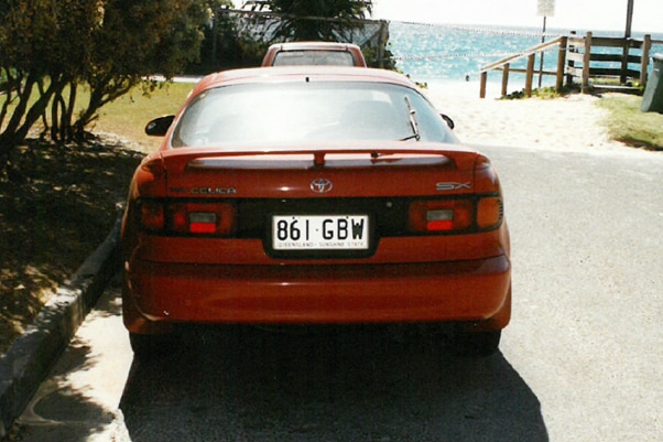 A red car parked near the beach