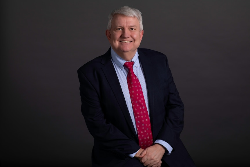 A man in a suit smiles for a professional portrait.