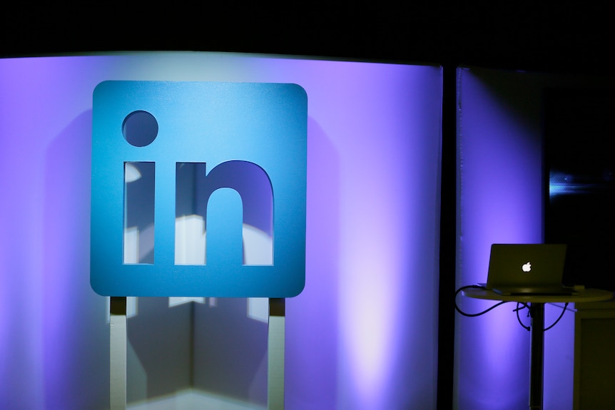 A blue linkedin logo illuminated on a purple background