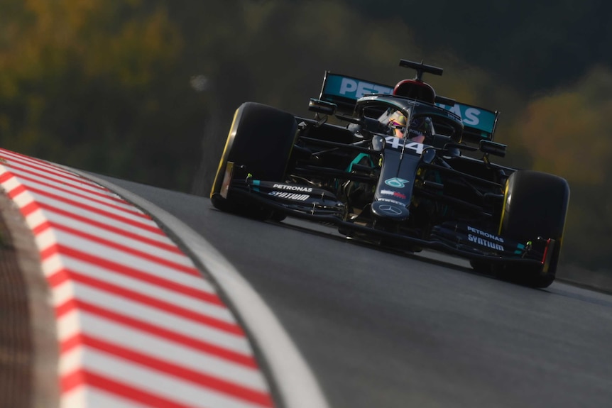 Lewis Hamilton drives a black car down a slick-looking track