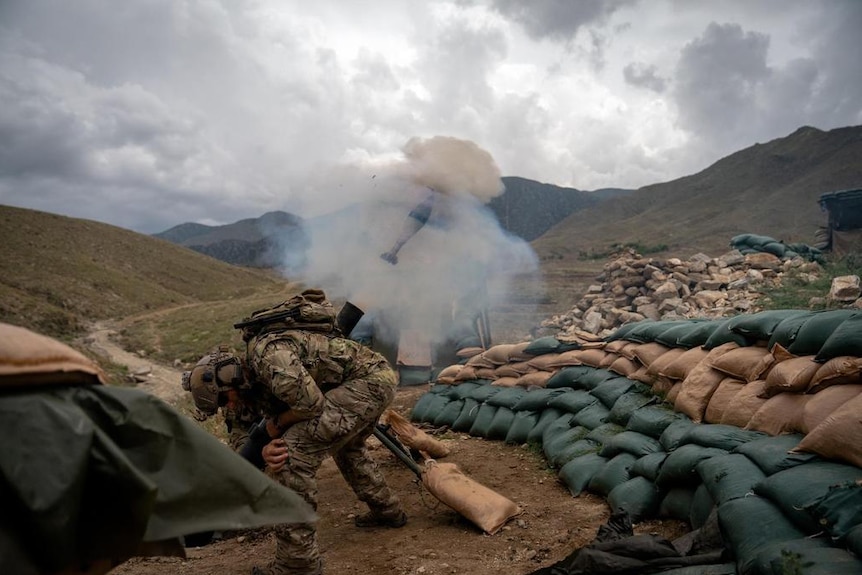 A United States Special Forces soldier turns away after firing  a 120mm mortar round from a military outpost in Afghanistan.