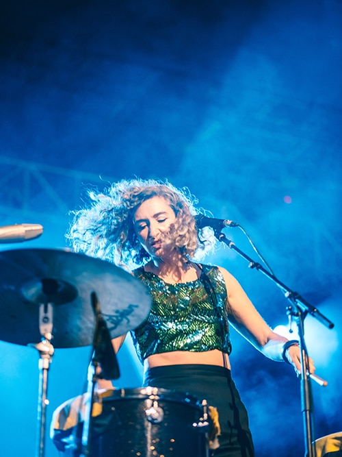 Danielle Caruana plays percussion on stage at Bluesfest 2022. Her hair flies about as she plays