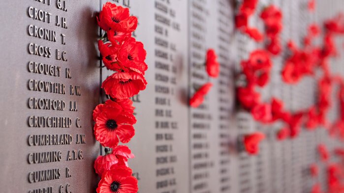 Poppies sit inserted beside War Memorial names on plaque