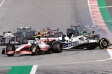F1 cars race at the start of a sprint, with one car being spun in the wrong direction after a collision.