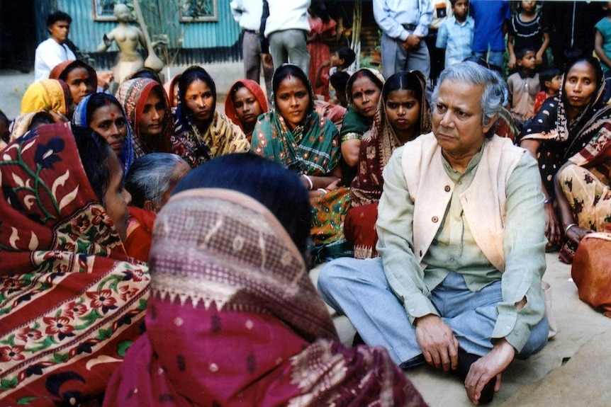 Professor Muhammad Yunus sits on the ground with Indian women