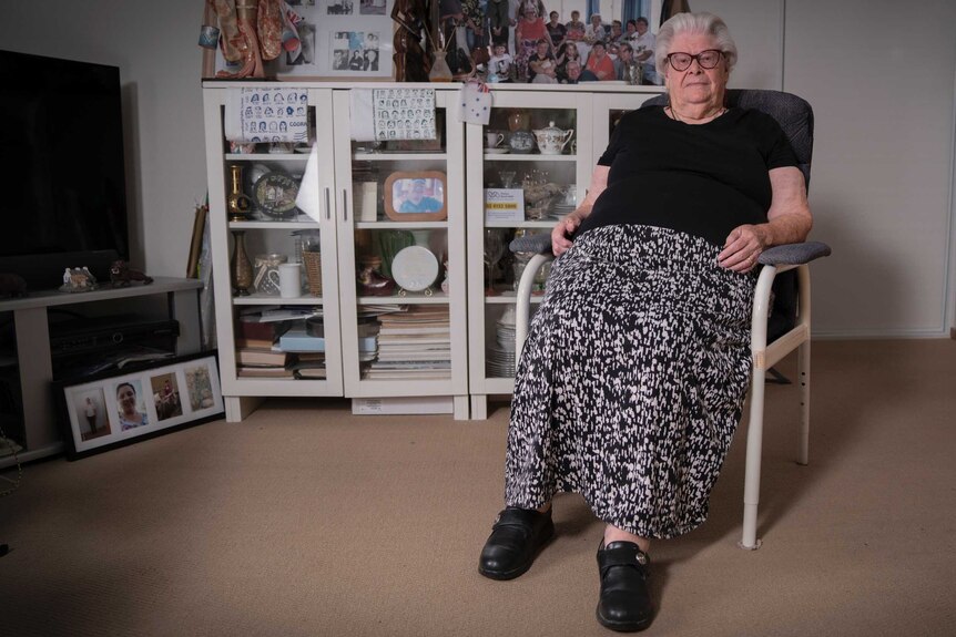 Patricia sits in a chair in her home, surrounded by family photos and memorabilia.