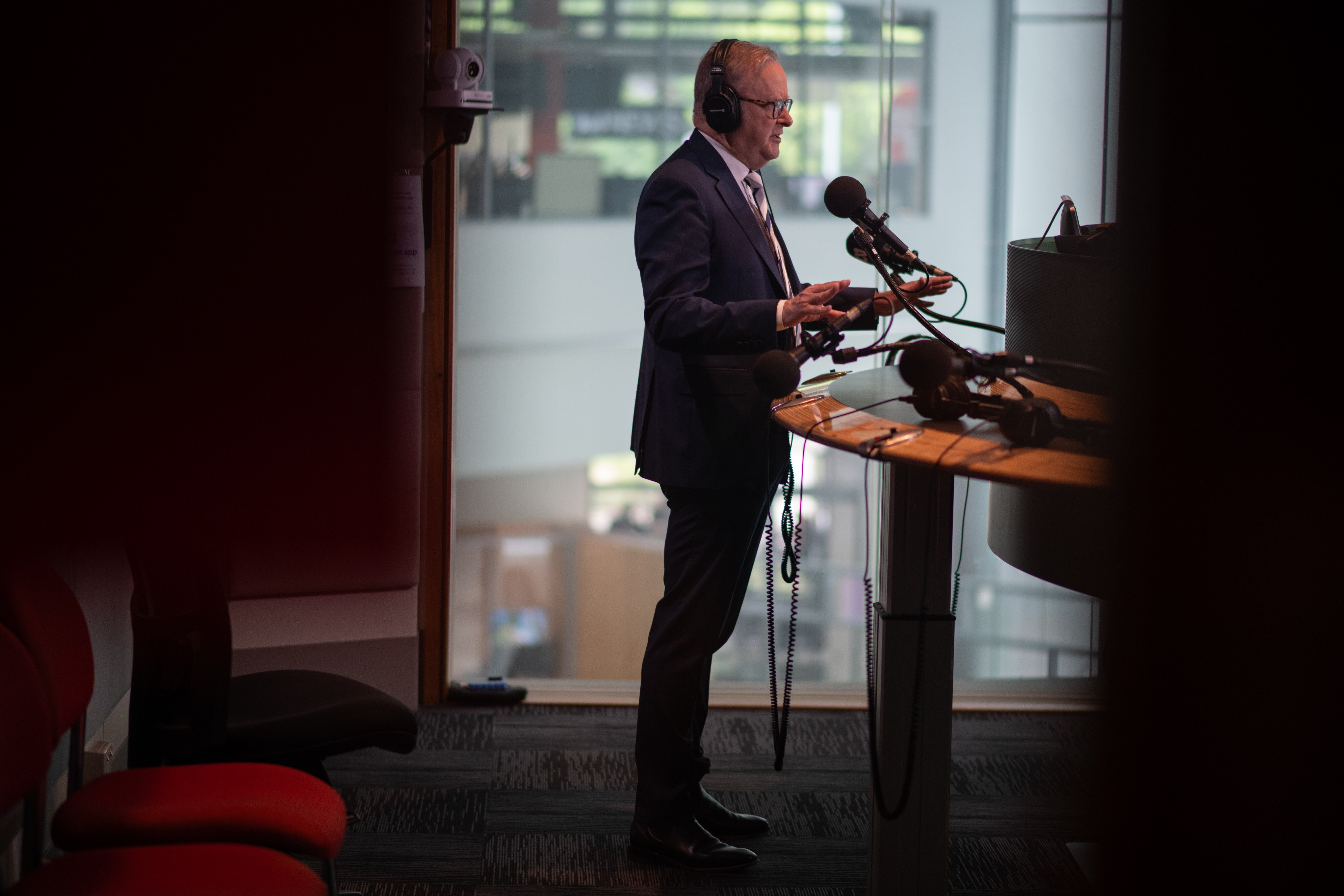 A man in a suit speaks in front of microphones