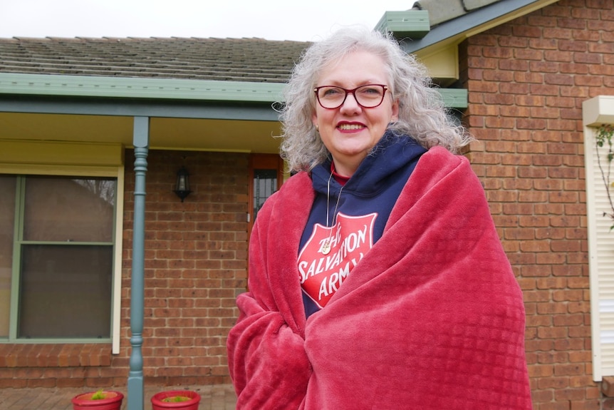 Woman standing in front of house wrapped in a blanket