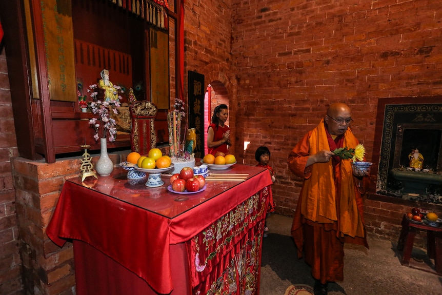 The visiting Vietnamese monk leads Wendy Tang and her daughter into the entrance chamber.