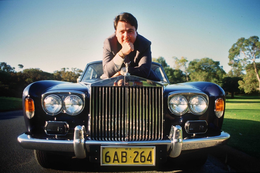 Mark Povey lies on the bonnet of a Rolls Royce car in an archive photo from the 1980s.