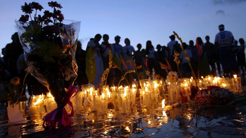 Survivors and families light candles on the first anniversary of the Bali bombings.