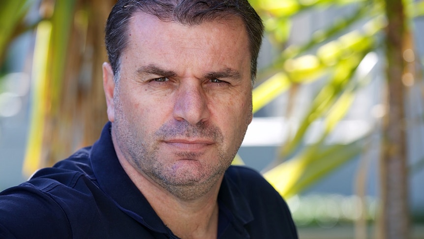 A portrait photo of a man looking straight to camera with serious facial expression