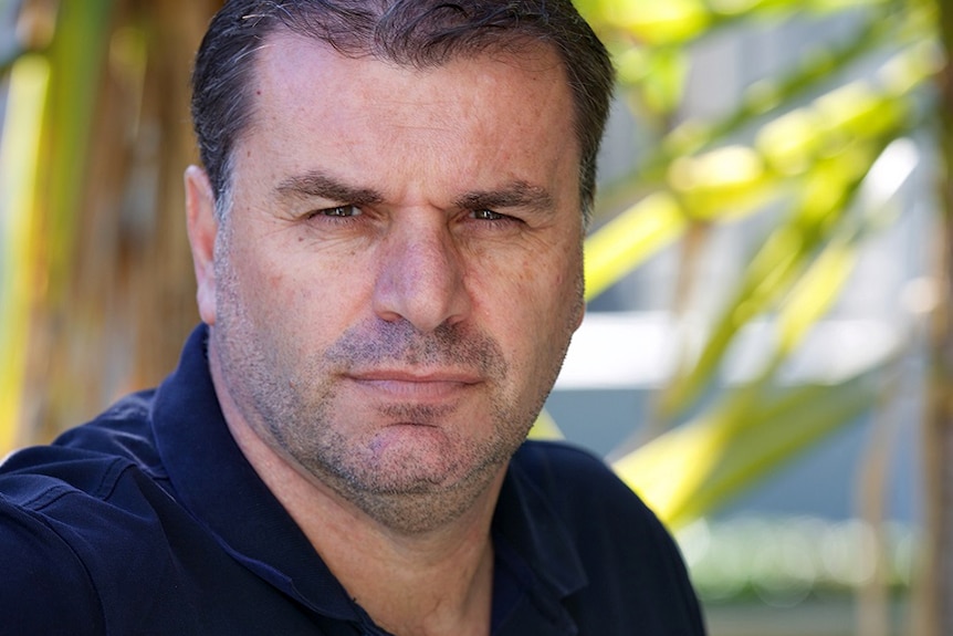 A portrait photo of a man looking straight to camera with serious facial expression