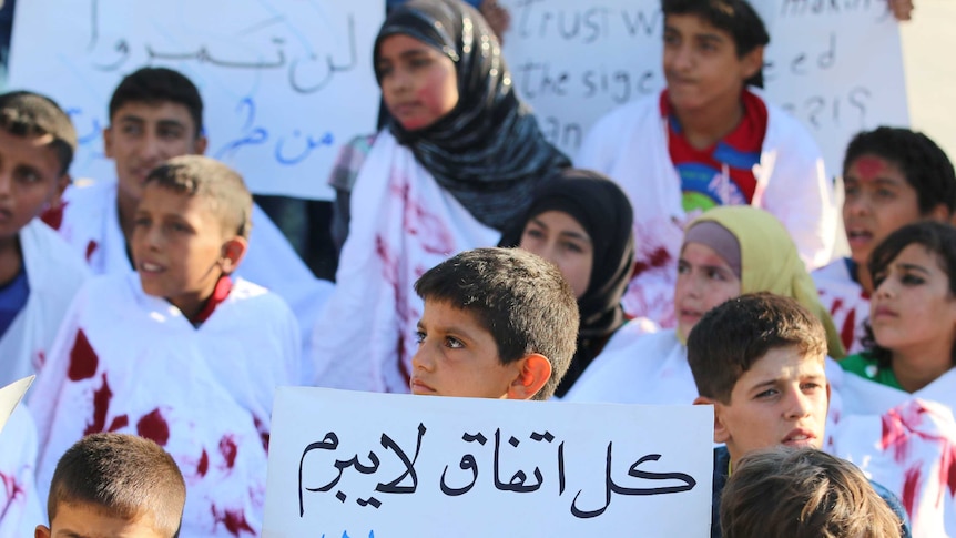 Children demonstrate against Syrian forces with a placard reading "every agreement which is not done with the rebels is void".