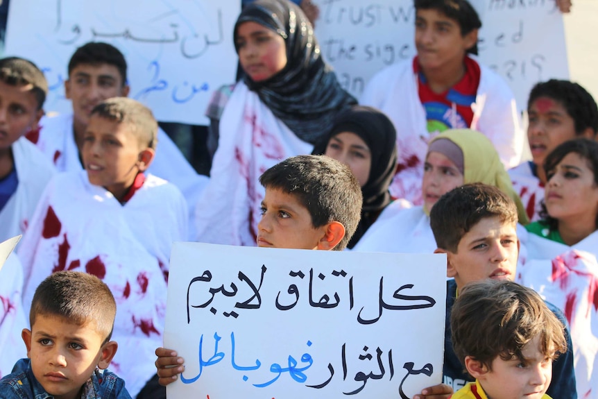 Children demonstrate against Syrian forces with a placard reading "every agreement which is not done with the rebels is void".