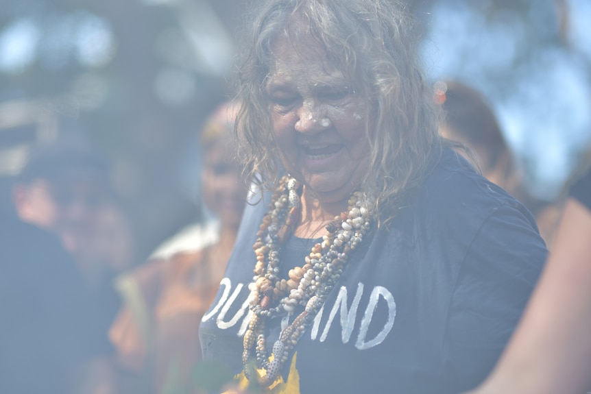 Larrakia traditional owner June Mills performs a smoke ceremony.
