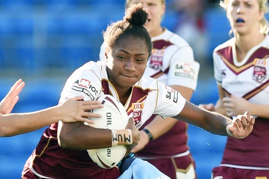 Amelia Kuk runs with the ball and tries to evade a NSW player.