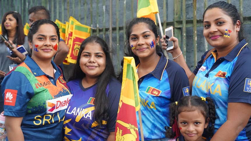 A group of women in Sri Lankan cricket fan shirts holding flags