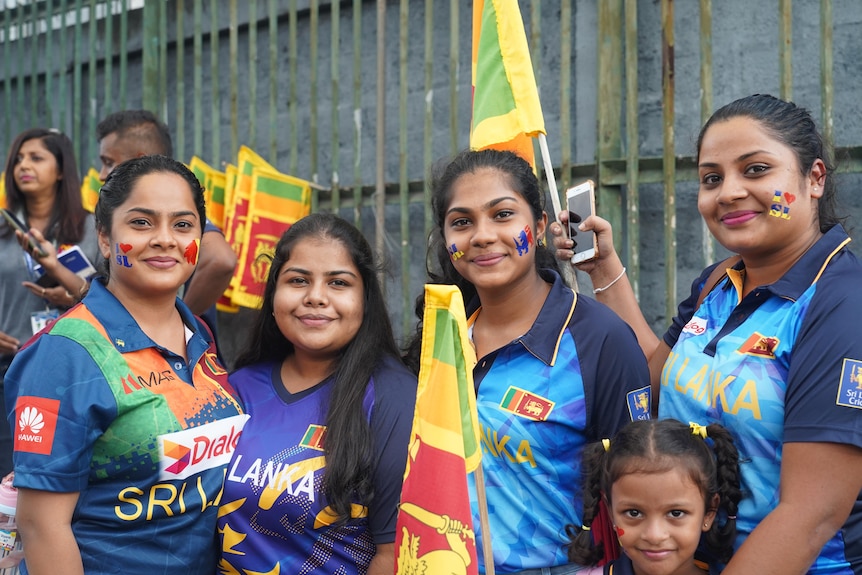 A group of women in Sri Lankan cricket fan shirts holding flags
