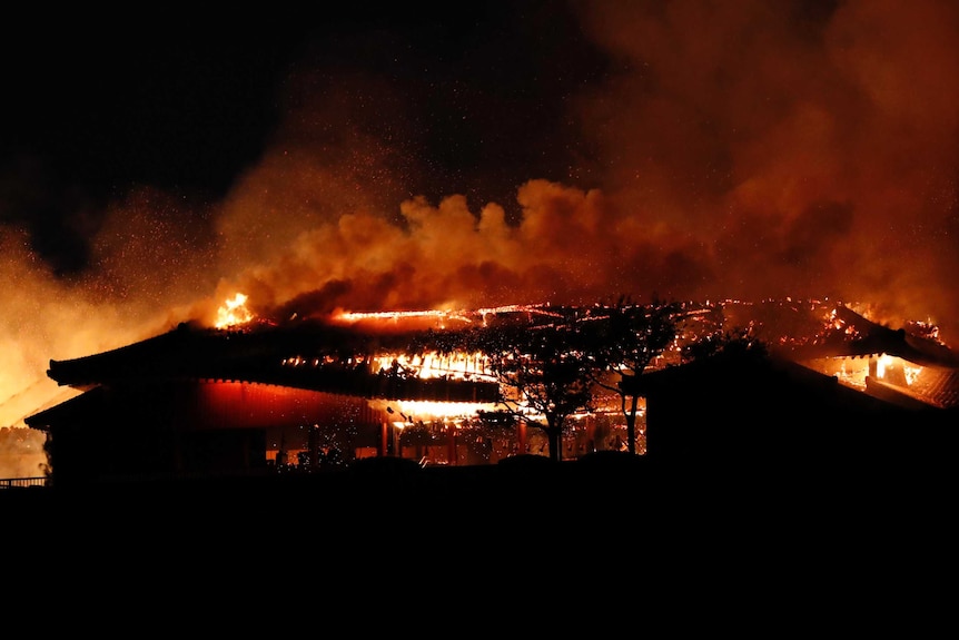 The Shuri Castle completely alight with fire, with smoke rising above its roof at night