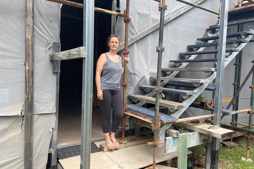 a woman stands next to a set of stairs on a construction site