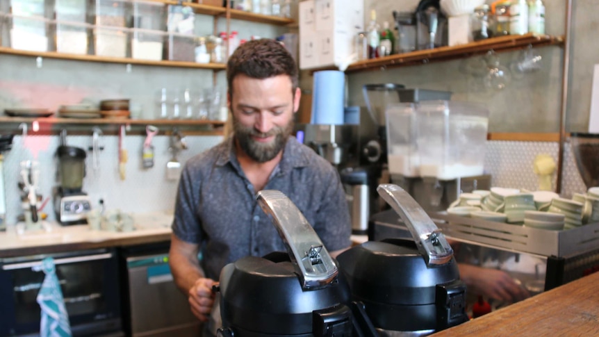 Co-owner of Braddon's Barrio cafe Sam burns making coffee at the coffee machine.
