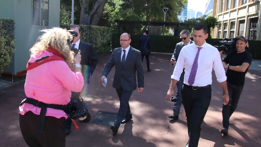 Barry Urban walks through the Parliament House forecourt surrounded by reporters and cameramen.