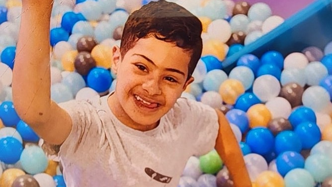 A boy smiling while sat in a ball pen
