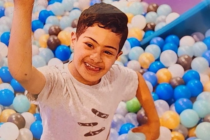 A boy smiling while sat in a ball pen