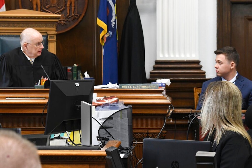 Kyle Rittenhouse sits in the stand, near Judge Bruce Schroeder.