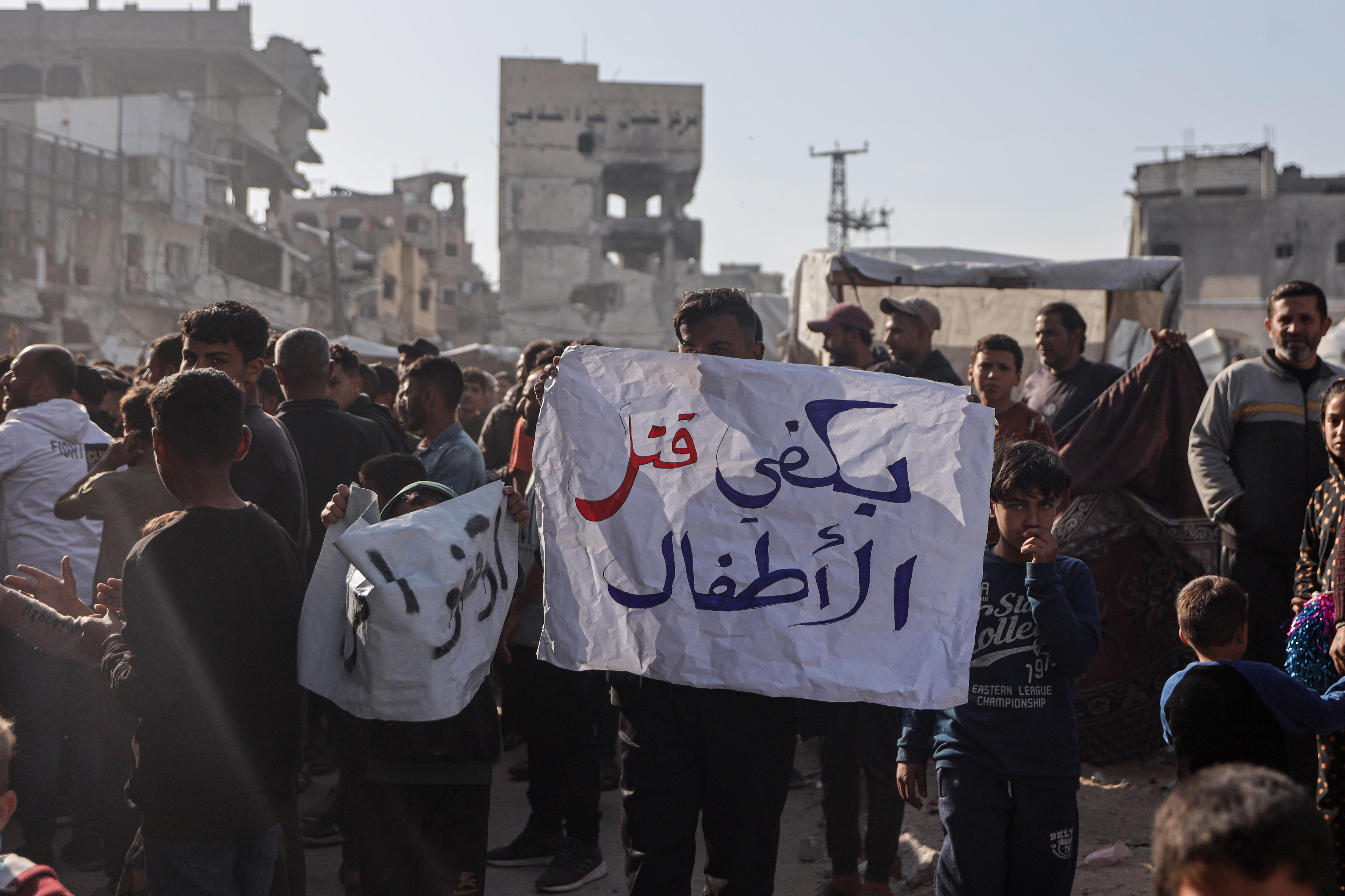 A man holding a sign that reads "Enough killing children".