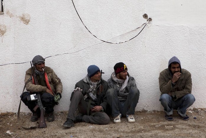 Libyan rebels sit at a checkpoint outside the city of Ajdabiyah