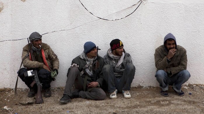 Libyan rebels sit at a checkpoint outside the city of Ajdabiyah