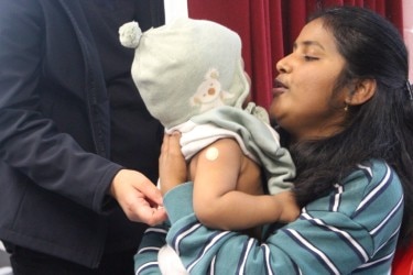 A woman holds her baby who's wearing a beanie