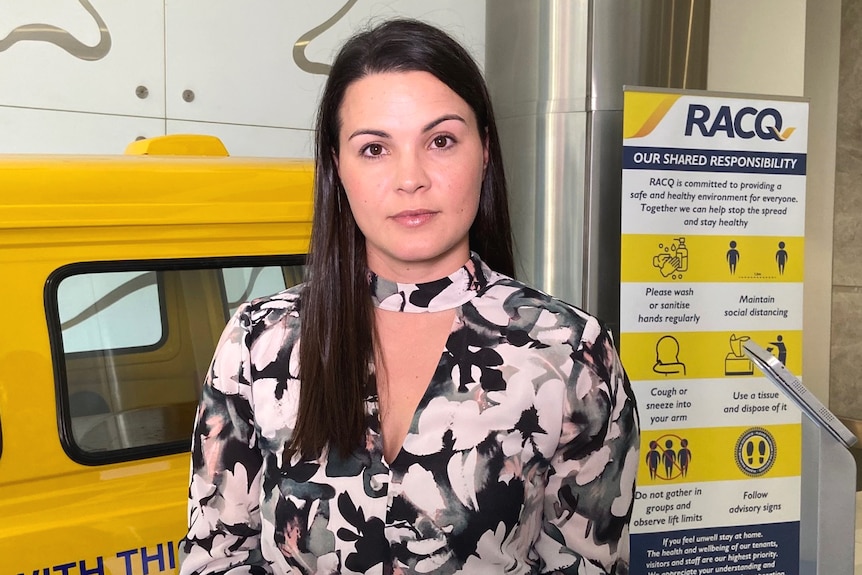 A woman standing in front of a van in the foyer of an RACQ building