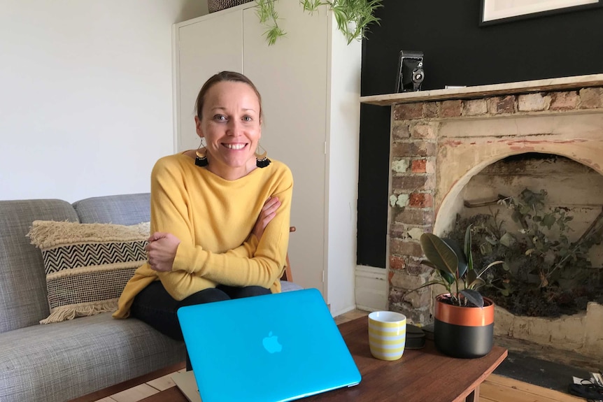 Erika McInerney sitting in her home with a laptop