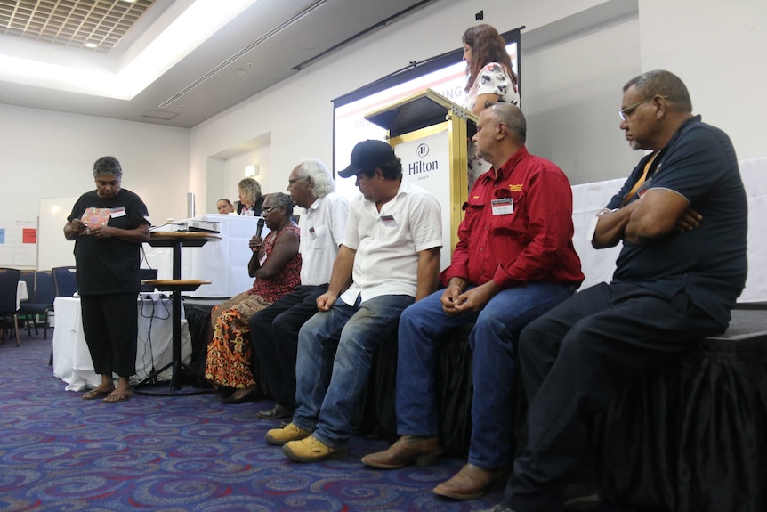 Six Indigenous leaders sit on a stage addressing an audience.