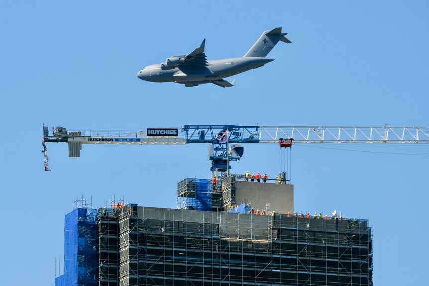 A plane flies over a construction site in Brisbane.