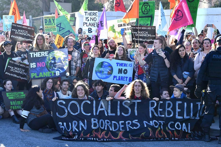 Climate protesters hold banners and stage a sit-in on a city street