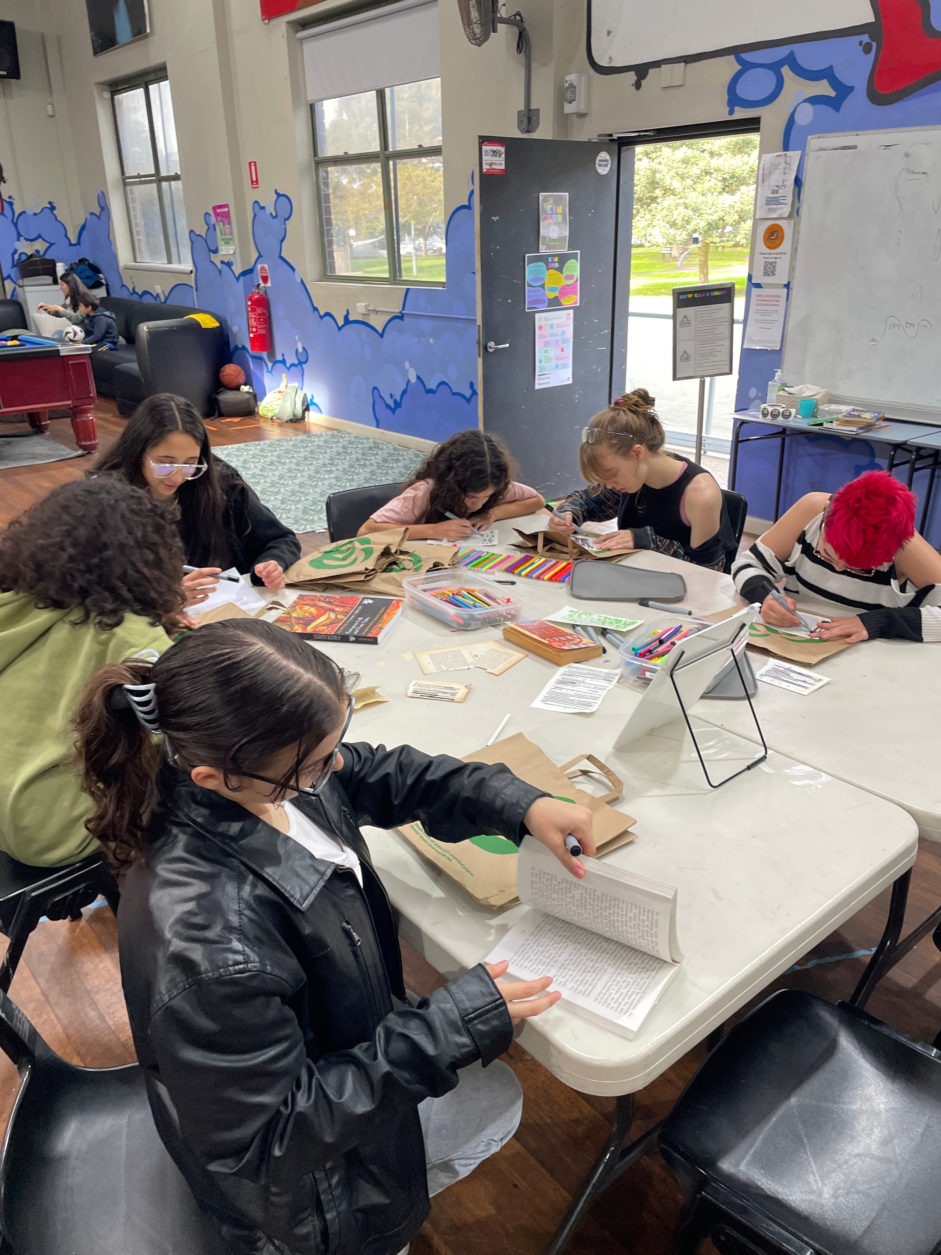 Группа студентов, являющихся частью KinHub, сидит за столом и работает в классе.